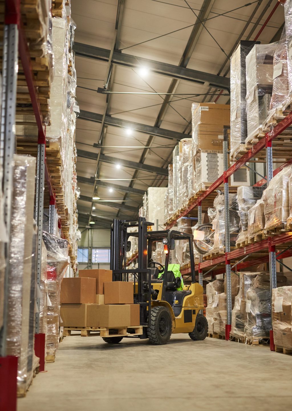 Vertical background image of warehouse interior with forklift carrying boxes
